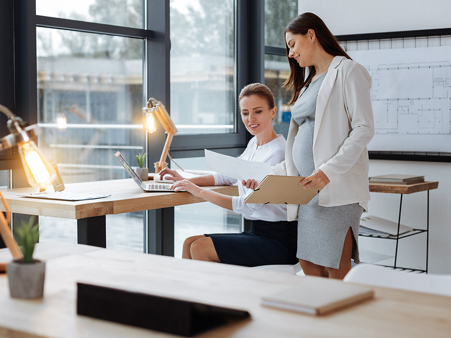 Pregnant businesswoman reviewing documents with another businesswoman